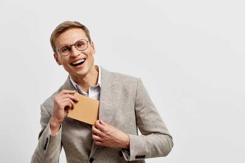 smiling young caucasian man wearing glasses holding credit card using mobile phone for cybersecurity digital protection concept on plain white background