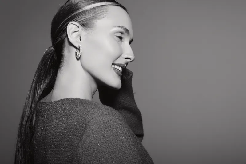 Profile portrait of a smiling Caucasian woman with light skin and long hair in casual sweater, looking away. Concept of happiness and natural beauty.