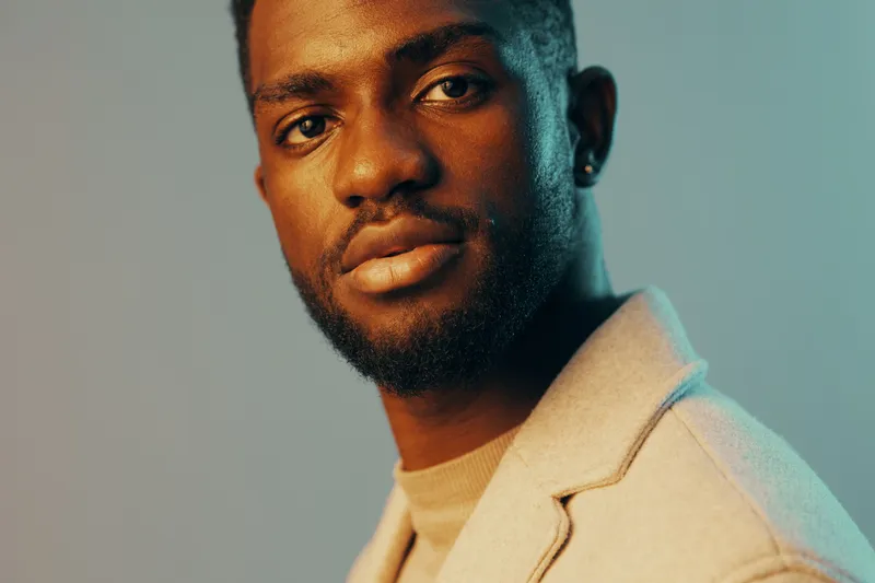 Stylish young Black man with a thoughtful expression in a modern setting, highlighting emotion and contemporary fashion trends