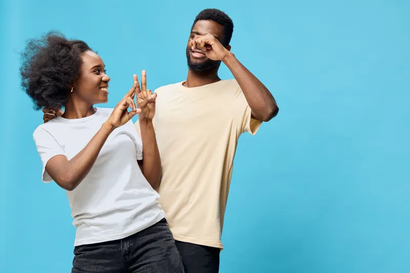 Happy young diverse couple having fun together against a blue background, showcasing joy and playful emotions, perfect for lifestyle and relationship themes