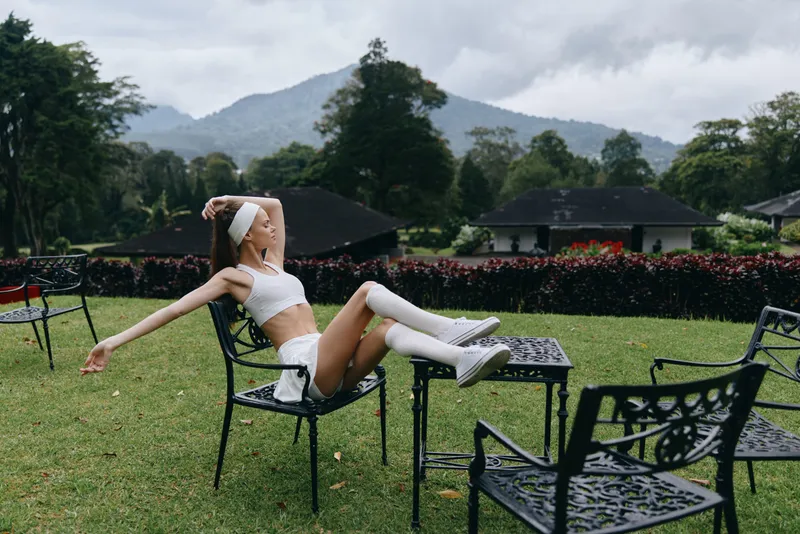 Stylish athletic model relaxing outdoors in a serene garden, wearing sporty clothing, embodying a carefree lifestyle amidst nature s beauty