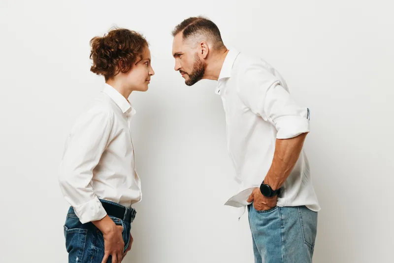 A professional man and business minded colleague face off on an isolated white background, conveying tension, focus, and competitive emotion in a corporate scene.