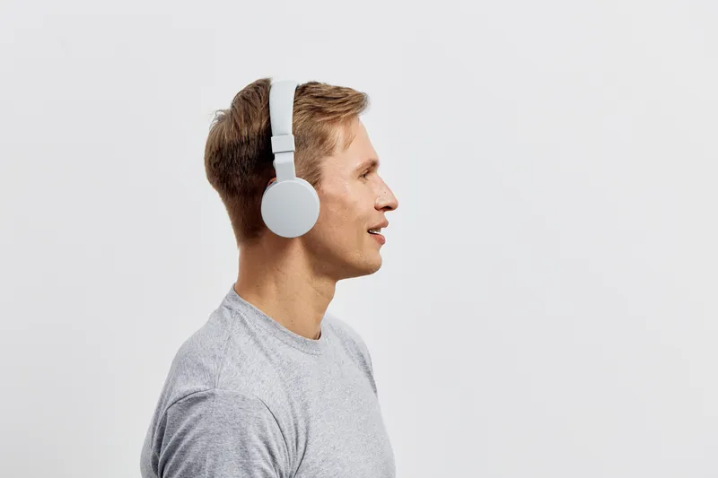 side view young smiling caucasian man wear gray tshirt white wireless headphones listen music isolated on light background digital detox concept