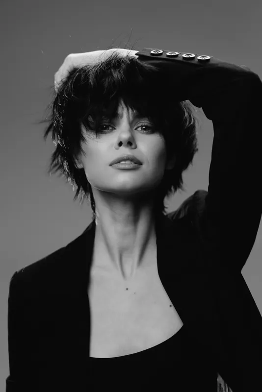 Black and white portrait of a stylish woman with short hair in a blazer expressing confidence and sophistication.