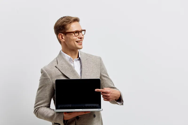 smiling man holding laptop point screen wear glasses checkered jacket white shirt isolated on plain background digital nomad technology concept