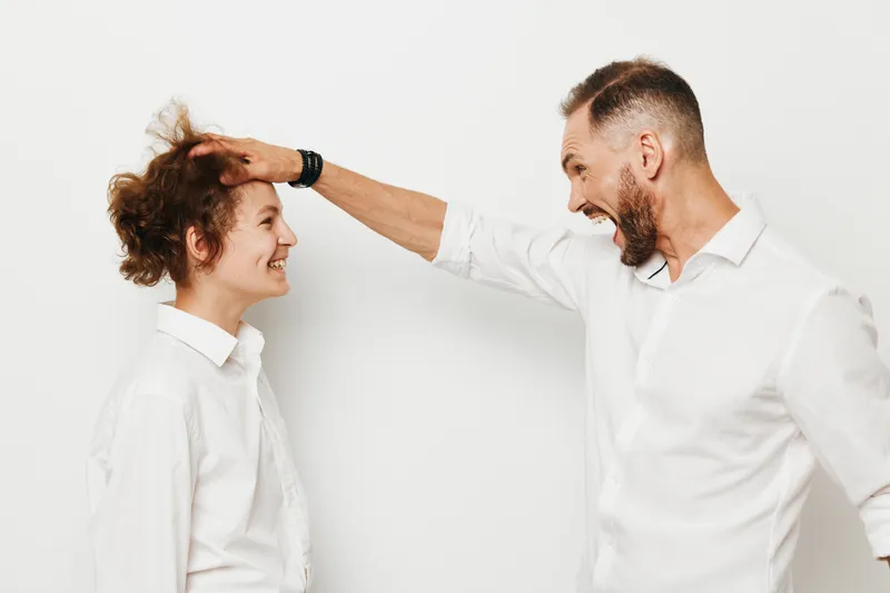 A business professional man interacts playfully with a colleague against an isolated colored background, expressing energy, focus, and positive teamwork in a modern setting.