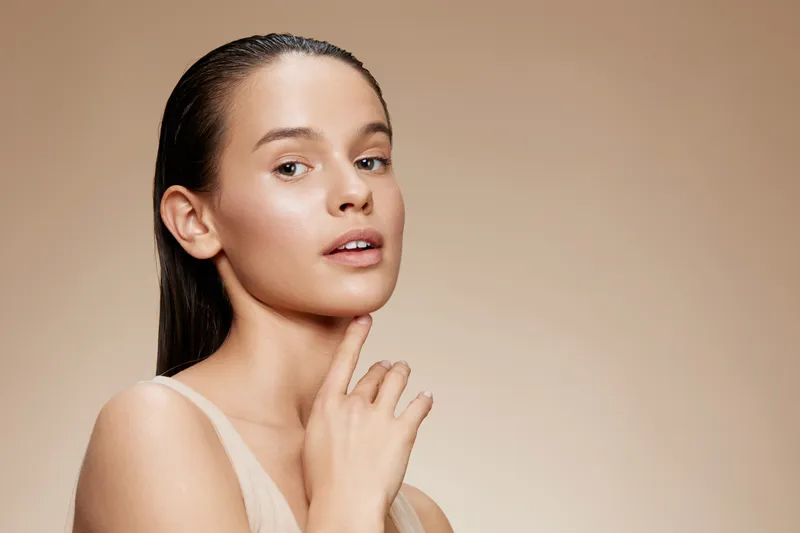 Portrait of a young Caucasian woman with long wet hair, showcasing a natural beauty look and neutral background, embodying confidence and elegance