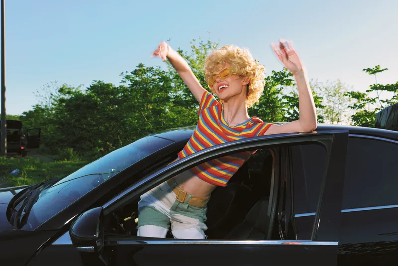 Woman lifestyle retro car joy, sunny colorful hair striped croptop, summer fashion, candid smile, freedom breeze, driving highway outdoor leisure, vibrant energy, window sunshine, casual style
