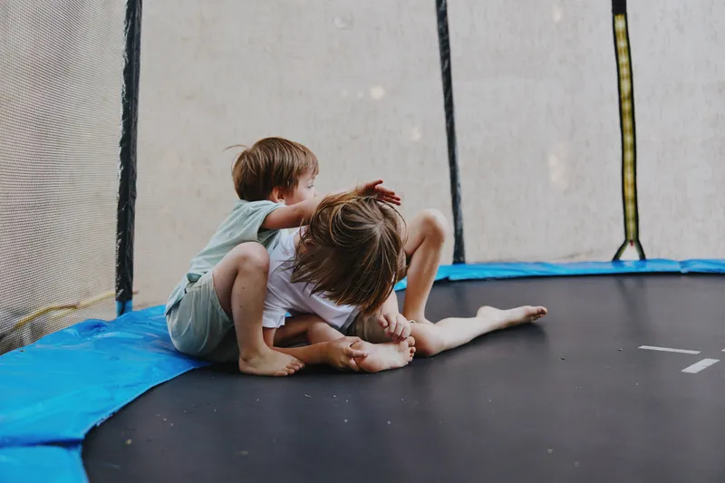 Playful children on trampoline, enjoying laughter and fun during sunny day. Perfect for capturing the joy of childhood and outdoor activities.