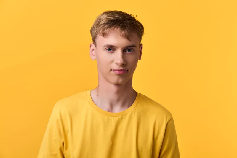 Yellow background and shirt with a young male model in a clean studio, minimal setup, bright casual look, soft lighting and modern style, clear focus on face and expression