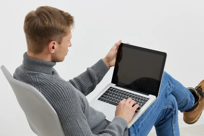 young man using laptop casual wear sit chair work remote freelance digital nomad concept