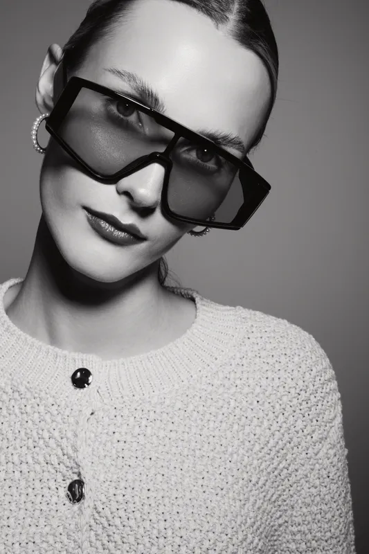 Portrait of a young white woman with pale skin wearing oversized sunglasses and a knitted sweater. Studio fashion concept for style, elegance, and modern eyewear trends.