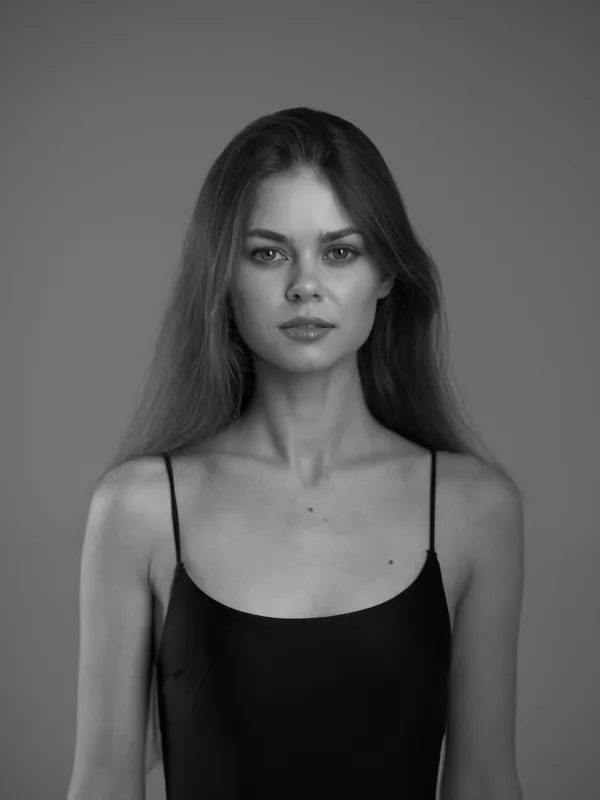 black and white portrait of a woman with long hair wearing a black dress looking serious