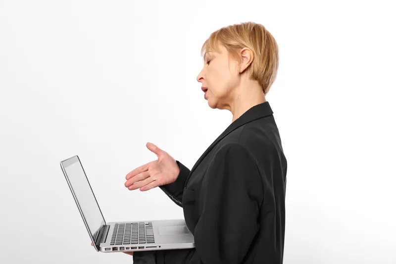 Woman in black blazer works on laptop, business communication in side profile, gesturing and working, isolated on white background, modern technology.