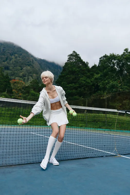 Young woman playing tennis on a cloudy day, wearing a sporty outfit, showcasing joy and athleticism, ideal for sports related concepts or healthy lifestyle themes