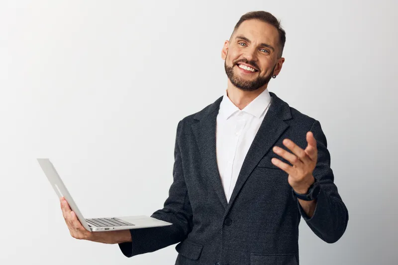 A confident, professional man in a textured blazer holds a laptop, presenting enthusiasm and focus against a clean colored background, conveying business expertise.