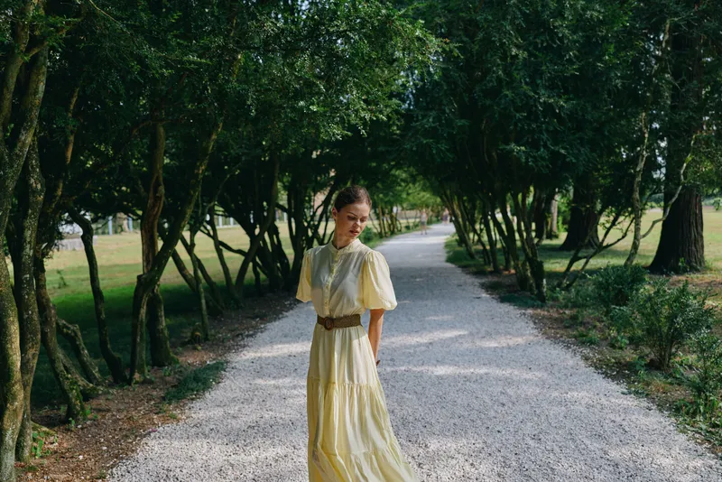 woman dress park pathway authenticity inclusivity trees nature, candid portrait of a woman in yellow dress walking on a gravel path