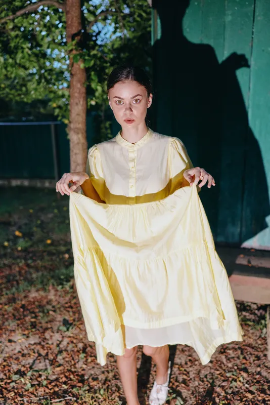 Woman portrait holding yellow dress outdoors at twilight, authenticity inclusivity present