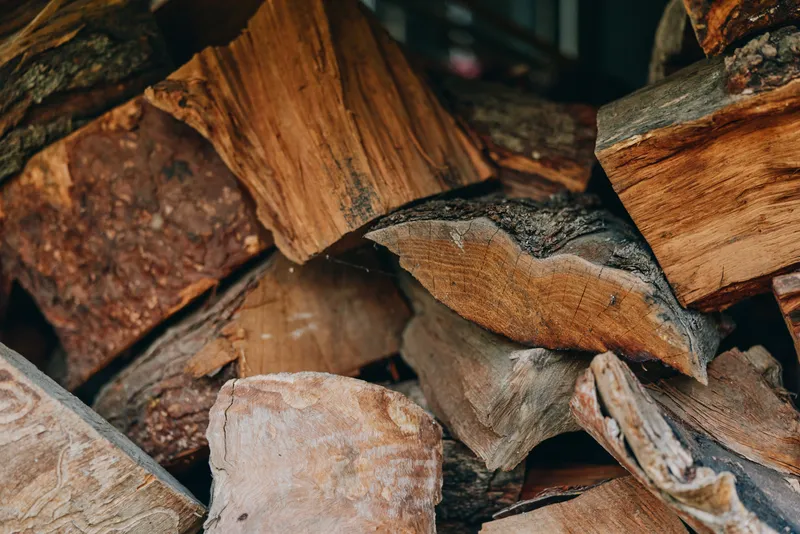 firewood, stacked wood, chopped logs, split logs, woodpile, timber - Closeup of seasoned firewood stack with rough bark and sawn ends beside a rustic cabin, cozy autumn supply for fireplace fuel.