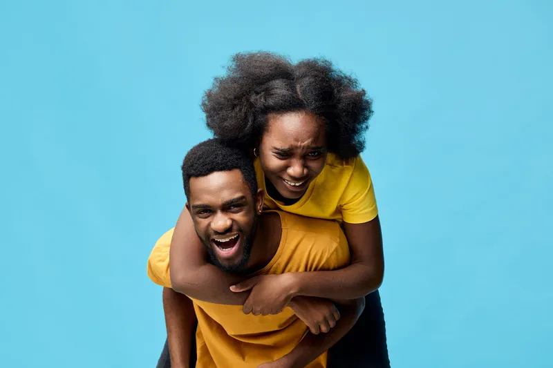 Happy couple laughing together against a bright blue background, showcasing joy and love, perfect for seasonal celebrations or romantic themes
