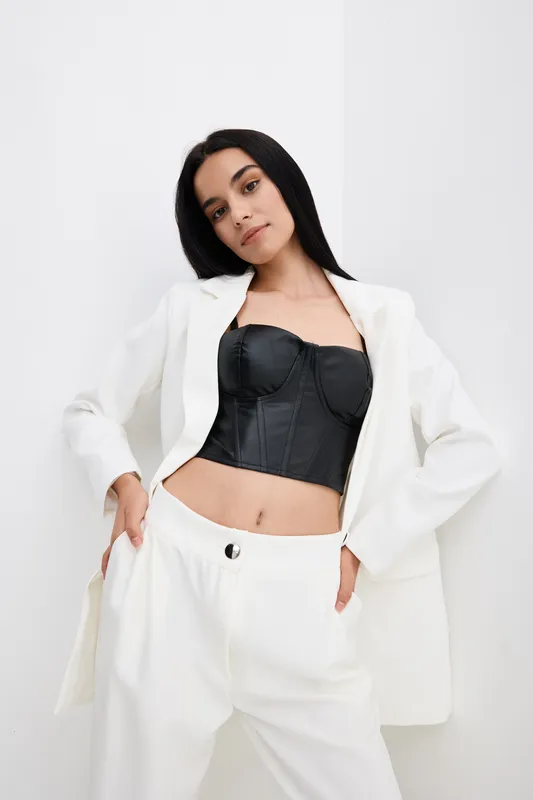 young woman in white suit and black corset posing against white background, stylish outfit, confident look, contemporary fashion portrait