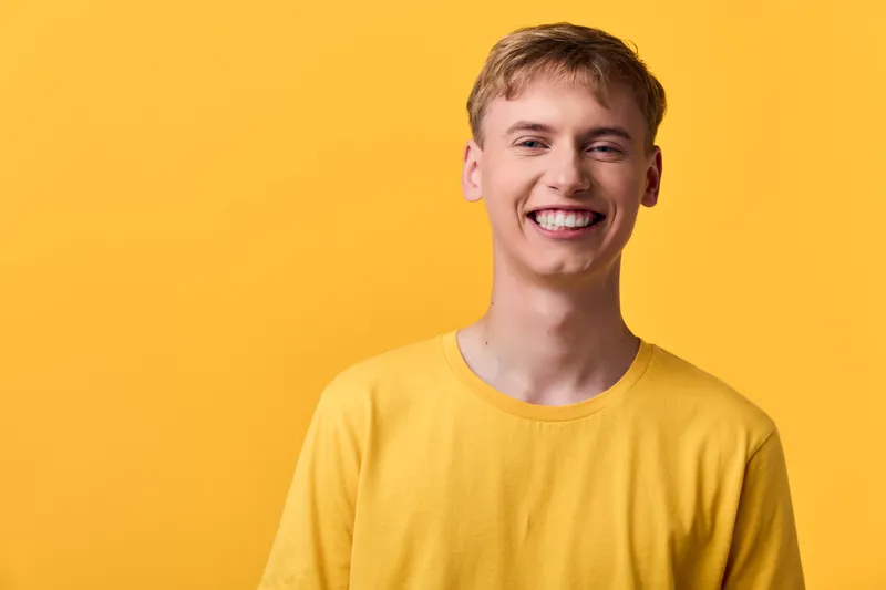 Bright smile of a young man in a yellow tee against a vivid yellow backdrop, conveying positivity, confidence, and casual charm for lifestyle, fashion, or marketing uses.