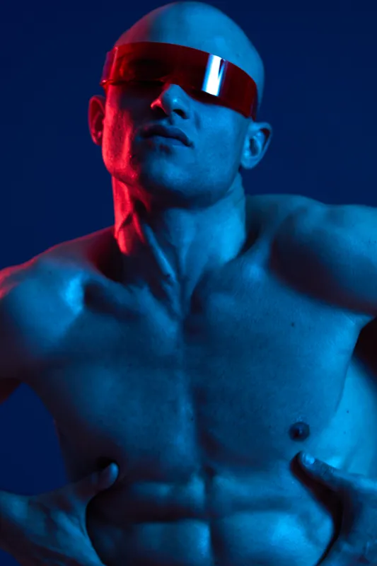 Strong man with sunglasses posing dramatically, showcasing an artistic blend of vibrant colors and striking lighting. Perfect for modern fashion and lifestyle themes.
