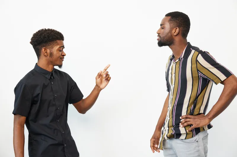 Two African American men engaging in a lively conversation, showcasing expressions of joy and enthusiasm, set against a plain white background.