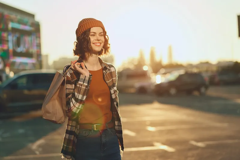 woman shopping with beanie and smile in urban sunset scene, candid lifestyle portrait capturing authenticity and golden hour glow, mindful living vibe and emotional storytelling moment