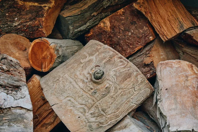 Firewood wooden logs wood texture chopped wood log pile bark closeup of stacked chopped hardwood for fireplace fuel, rustic outdoor timber, seasonal winter preparation, natural grain.