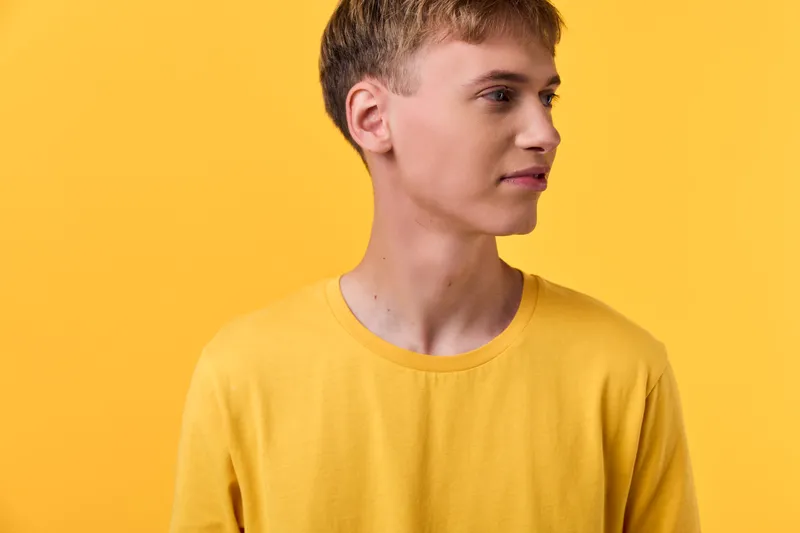 Male wearing a yellow shirt against a bright yellow background, simple studio setup, clean lines, fashion look, casual style, vibrant color emphasis, minimal wardrobe details, ideal for lifestyle and