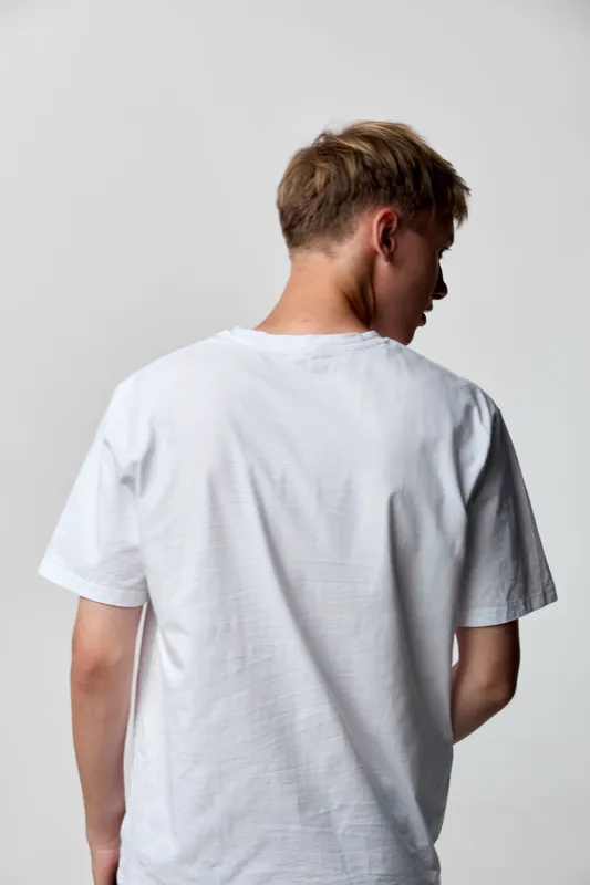 Back view of man wearing a white t shirt in a studio, casual clothing and a clear silhouette against a neutral background with soft lighting and relaxed pose.