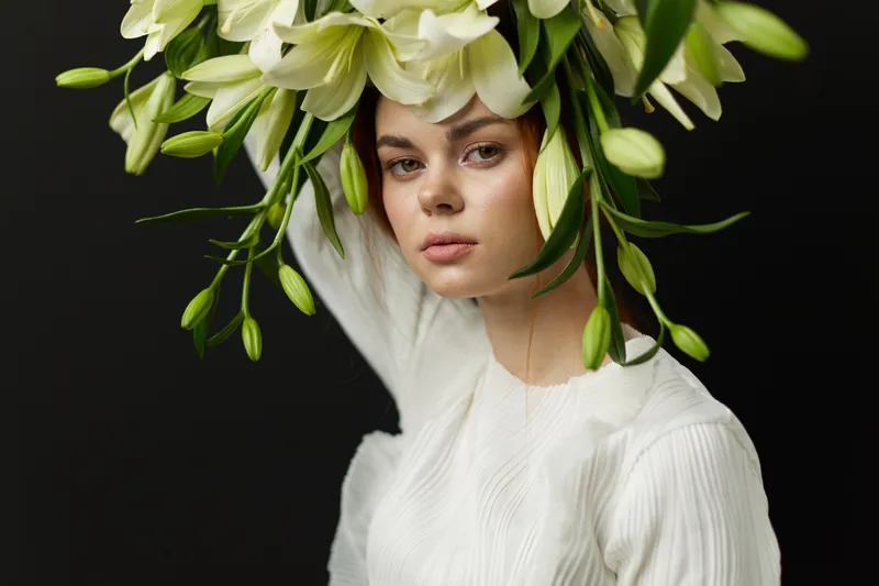 Ethereal portrait of a woman with a floral headdress made of white lilies, conveying tranquility and elegance against a dark background