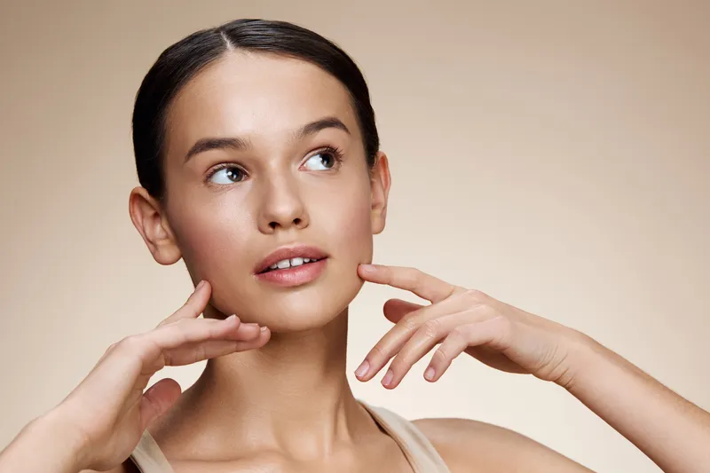 Young female model showcasing a serene expression, emphasizing skincare and beauty with a neutral background and soft lighting, perfect for wellness and natural beauty concepts