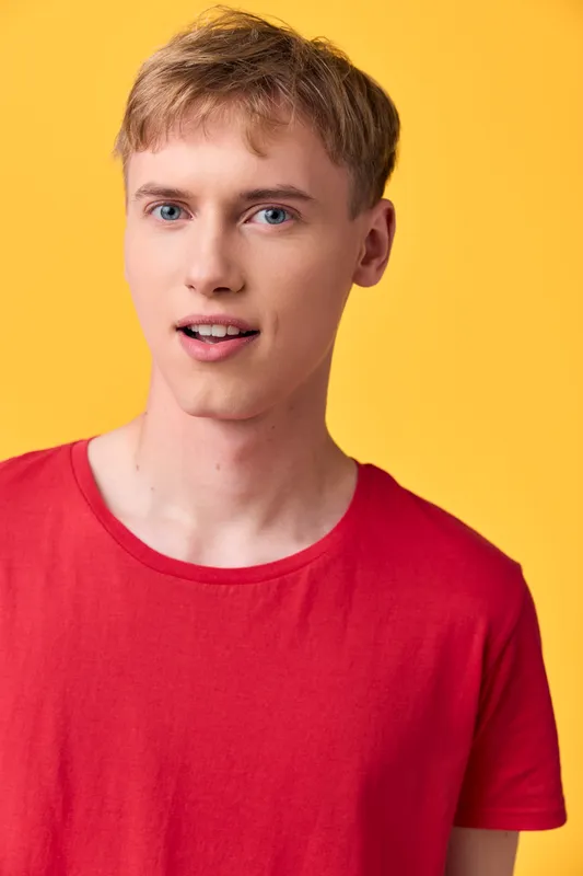 Man in casual red shirt against a vibrant yellow background, close up headshot with a youthful expression, clean modern look for fashion, lifestyle and stock photography