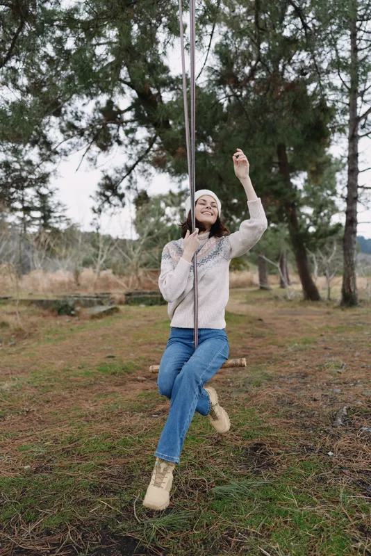 woman outdoor rope swing nature playful adventure forest casual youth leisure scene captures a joyful moment in a park like setting with trees and open space