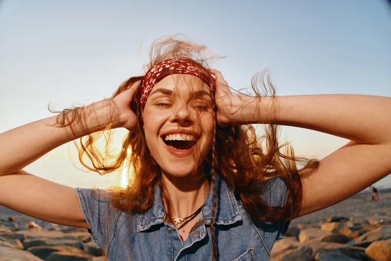 lifestyle woman with modern boho-western denim street style laughing joyfully with natural sunlight and warm film color tones outdoors
