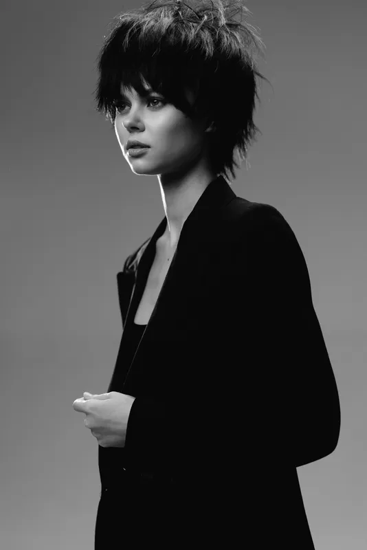 Black and white portrait of a young woman with short hair wearing a dark jacket with a serious expression