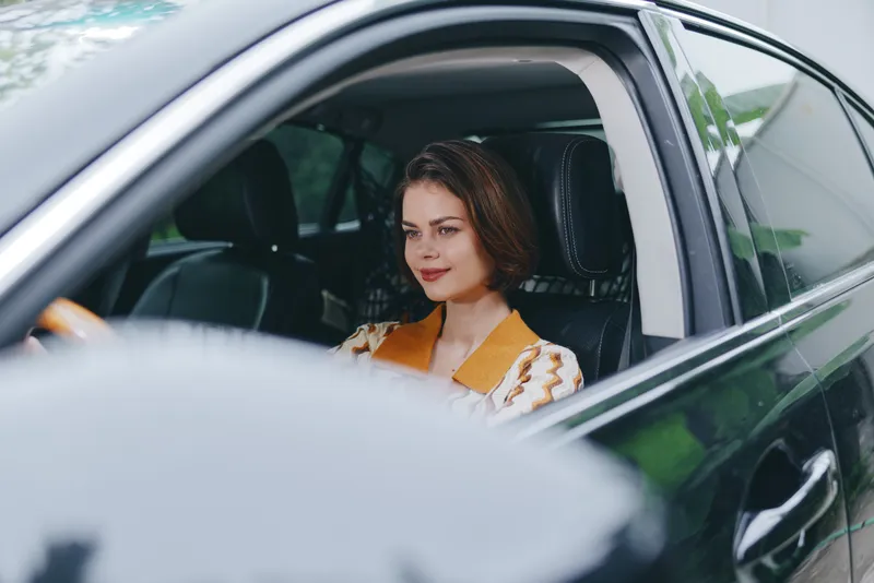 Car, driver, woman, smile a cheerful woman sits in the driver's seat with her hands on the wheel, radiating joy, confidence, and readiness for a journey inside a stylish interior