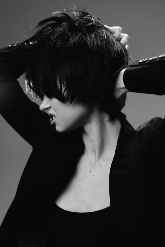 Black and white portrait of a woman with short hair expressing frustration or stress in studio lighting.