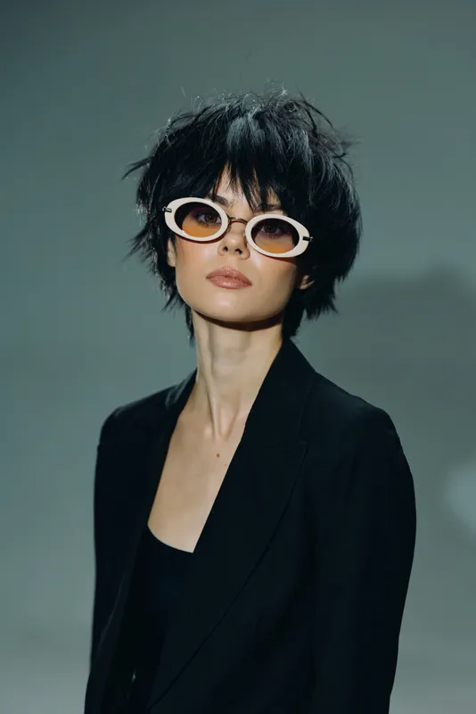 Stylish woman wearing sunglasses and a black jacket with a confident and calm expression