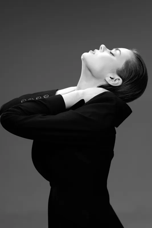 Black and white portrait of a woman in a suit with eyes closed and head tilted back expressing calmness