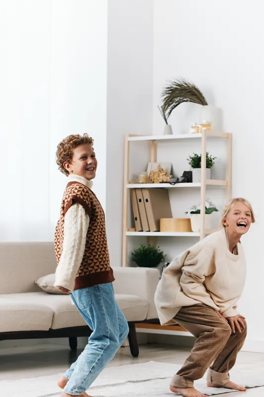 Authentic scene of children at play in a bright home, capturing school age curiosity and a warm lifestyle moment with joyful movement and candid smiles.