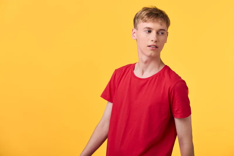 Red shirt, youthful figure against a vibrant yellow backdrop, casual pose and relaxed mood, studio fashion shot highlighting bold colors for lifestyle or product presentation