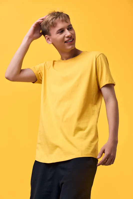 Smiling young male in a bright yellow t shirt standing against a vivid yellow background, casual summer style, relaxed pose, lifestyle and fashion mood for promotional projects