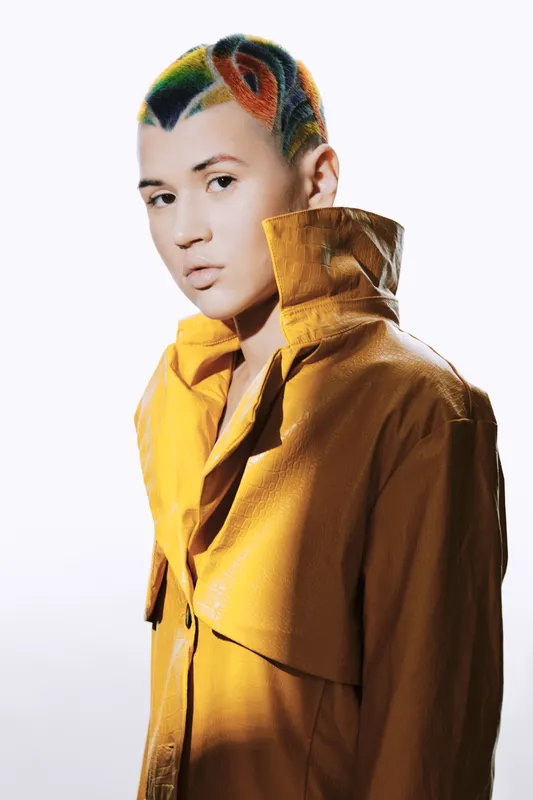 young woman with colorful creative haircut wearing mustard yellow jacket, looking thoughtfully, isolated on white background, modern fashion style