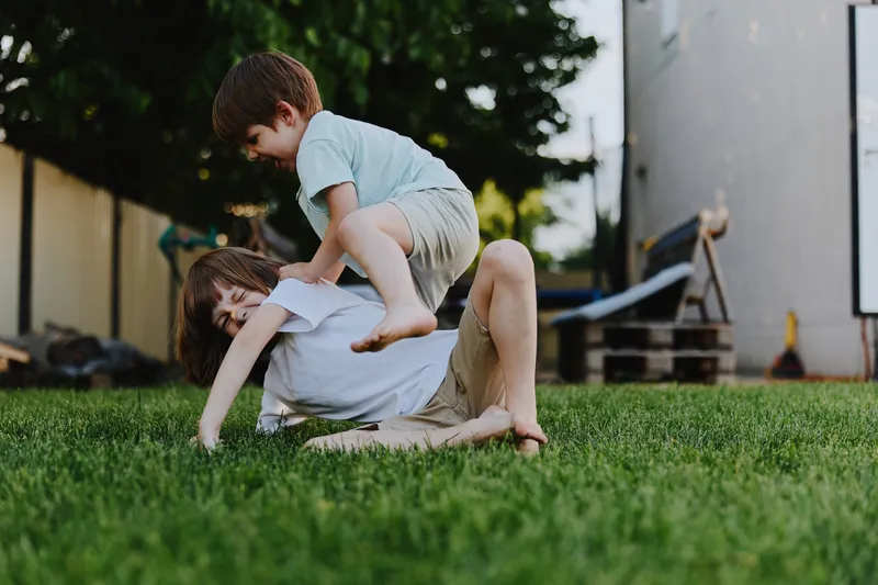 Playful children enjoying outdoor fun, depicting a joyful moment of friendship and laughter in a sunny garden setting, capturing childhood innocence and energy.