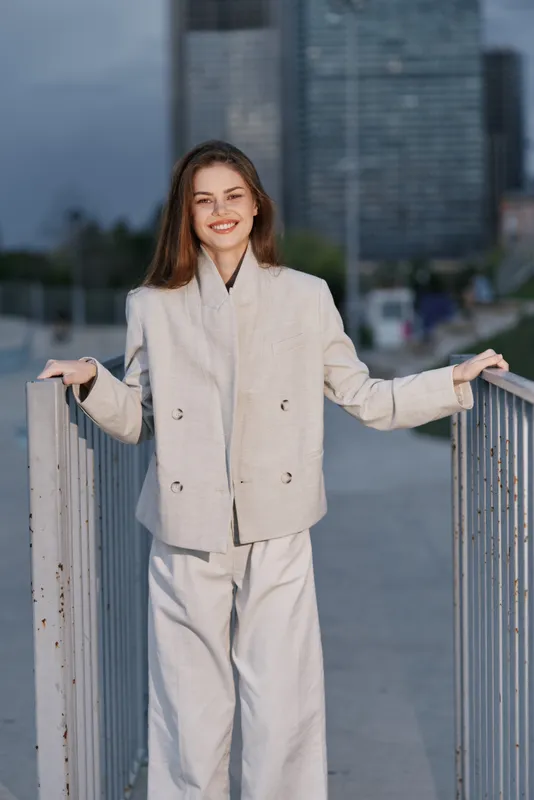 confident woman in beige business suit standing outdoors with urban background smiling