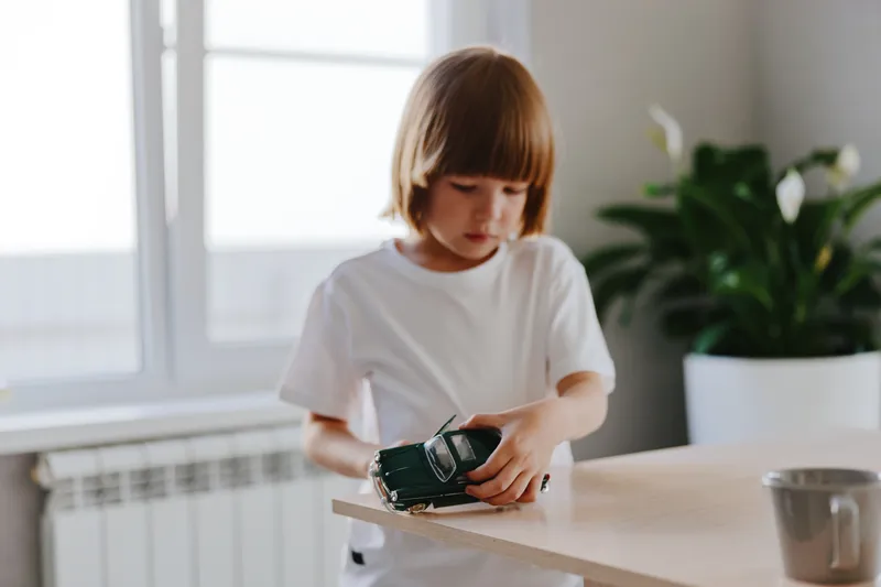 Young boy playing with a toy car indoors, engaging in imaginative play while exploring creativity in a warm and inviting space filled with natural light.