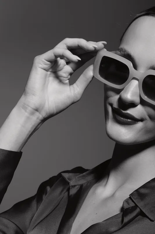 Closeup of fair skinned Caucasian woman wearing sunglasses and smiling in studio, concept for fashion and style.